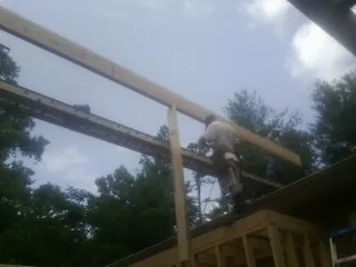 Carpenter setting a ridge beam over a new addition frame — Ice Dam Removal by Roofing Brothers in Naytahwaush