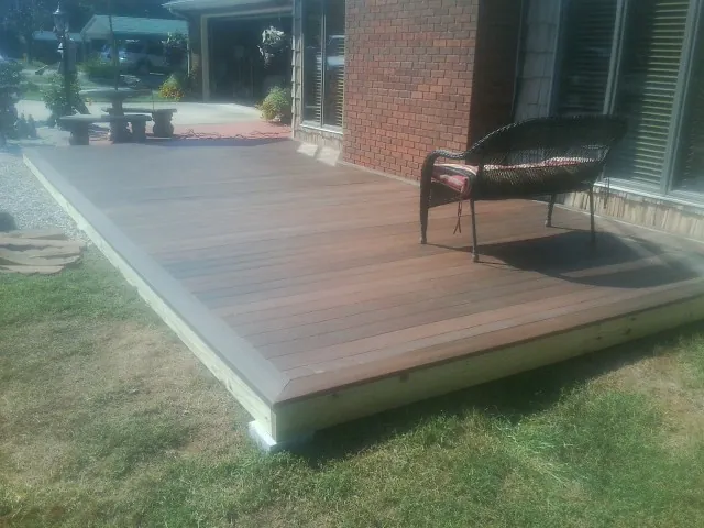 New wood deck and wicker chair beside a brick house in Naytahwaush