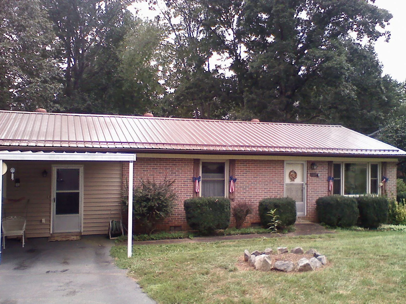 Bronze metal roof and carport on a brick ranch home — Roof Repair work by our crew in Naytahwaush