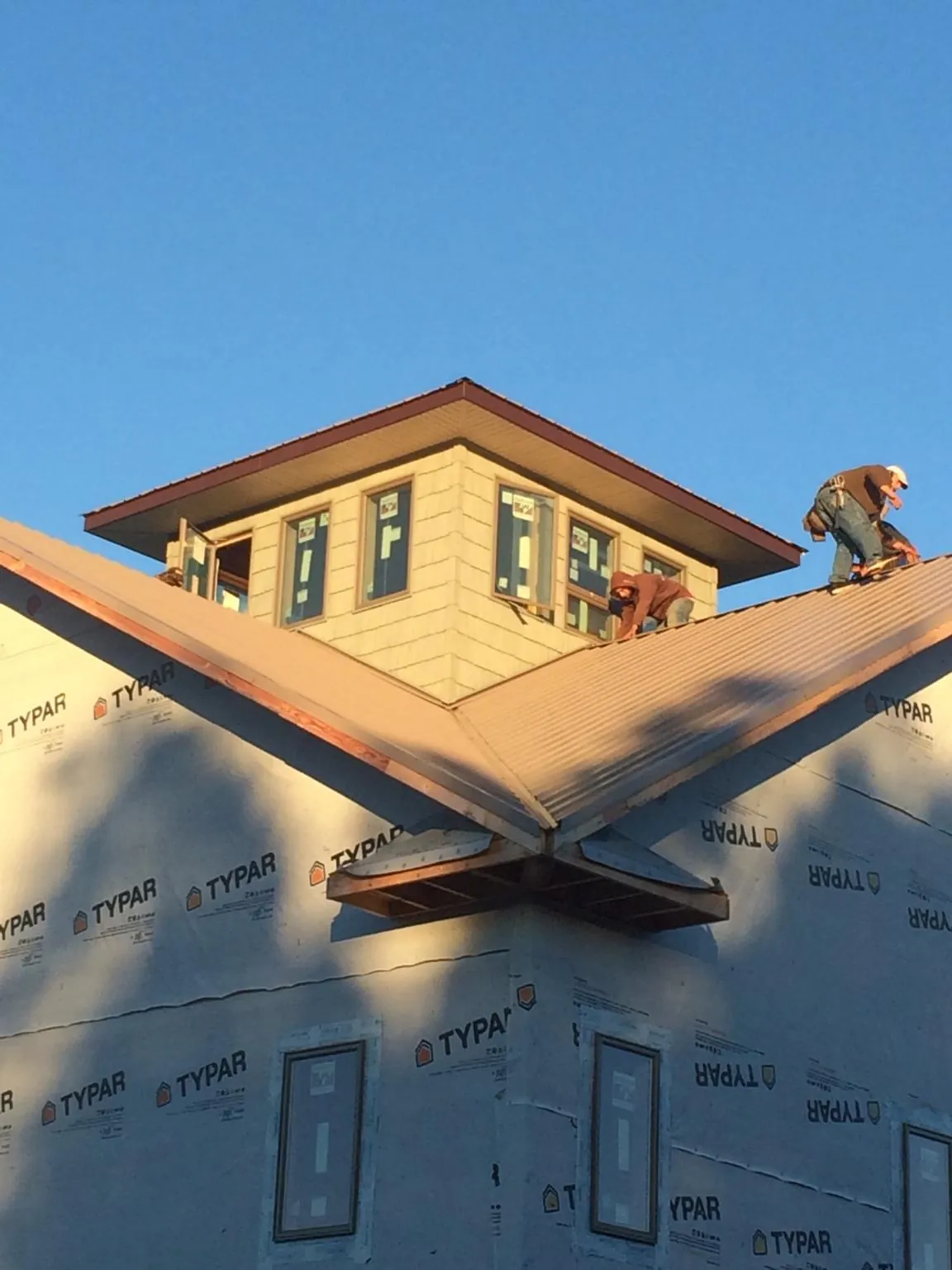 Roofers working around a rooftop cupola on a new metal roof at sunset — Roof Waterproofing in Naytahwaush by Roofing Brothers